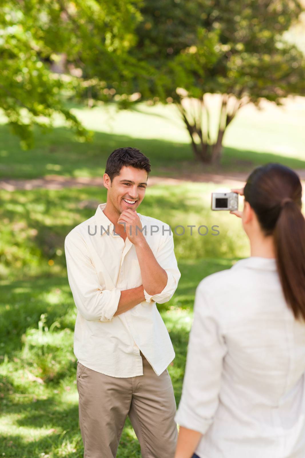 Woman taking a photo of her boyfriend in a park