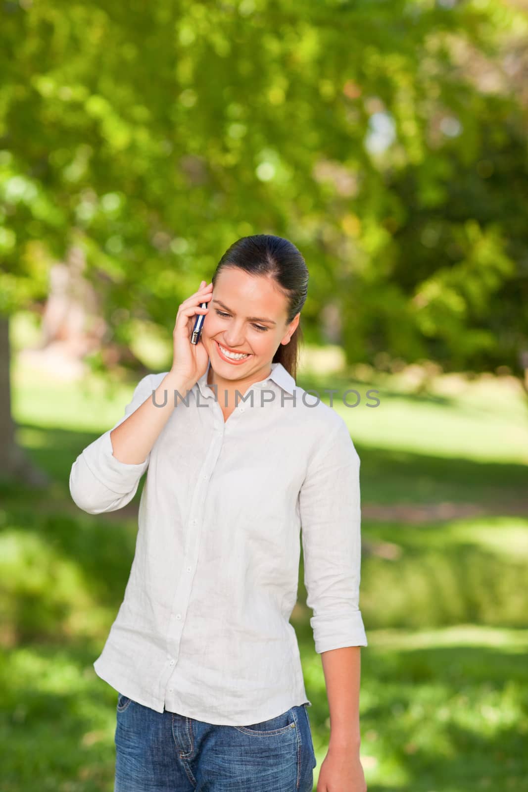 Young woman phoning in the park during the summer
