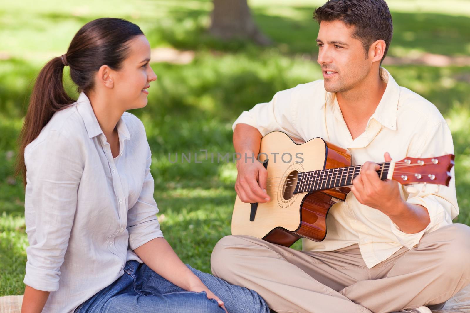 Romantic man playing guitar for his wife in a park