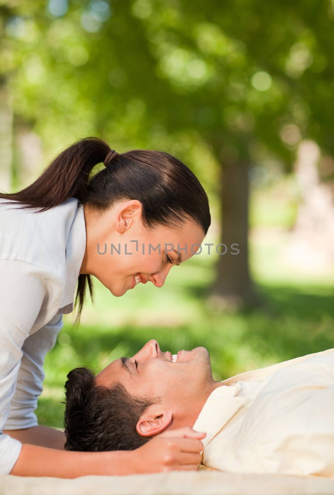 Happy couple lying down in the park during the summer