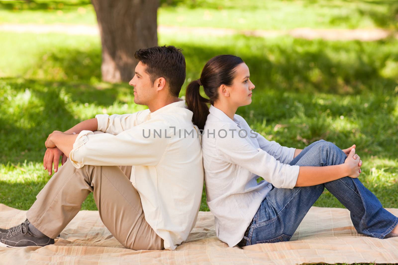 Couple sitting back-to-back in the park by Wavebreakmedia