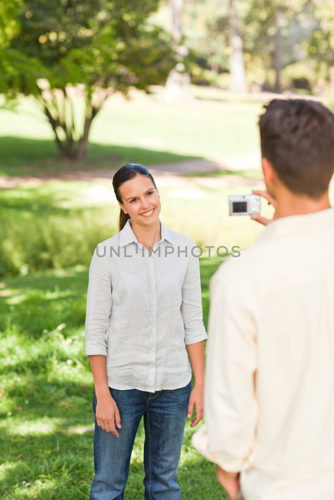 Man taking a photo of his girlfriend in a park