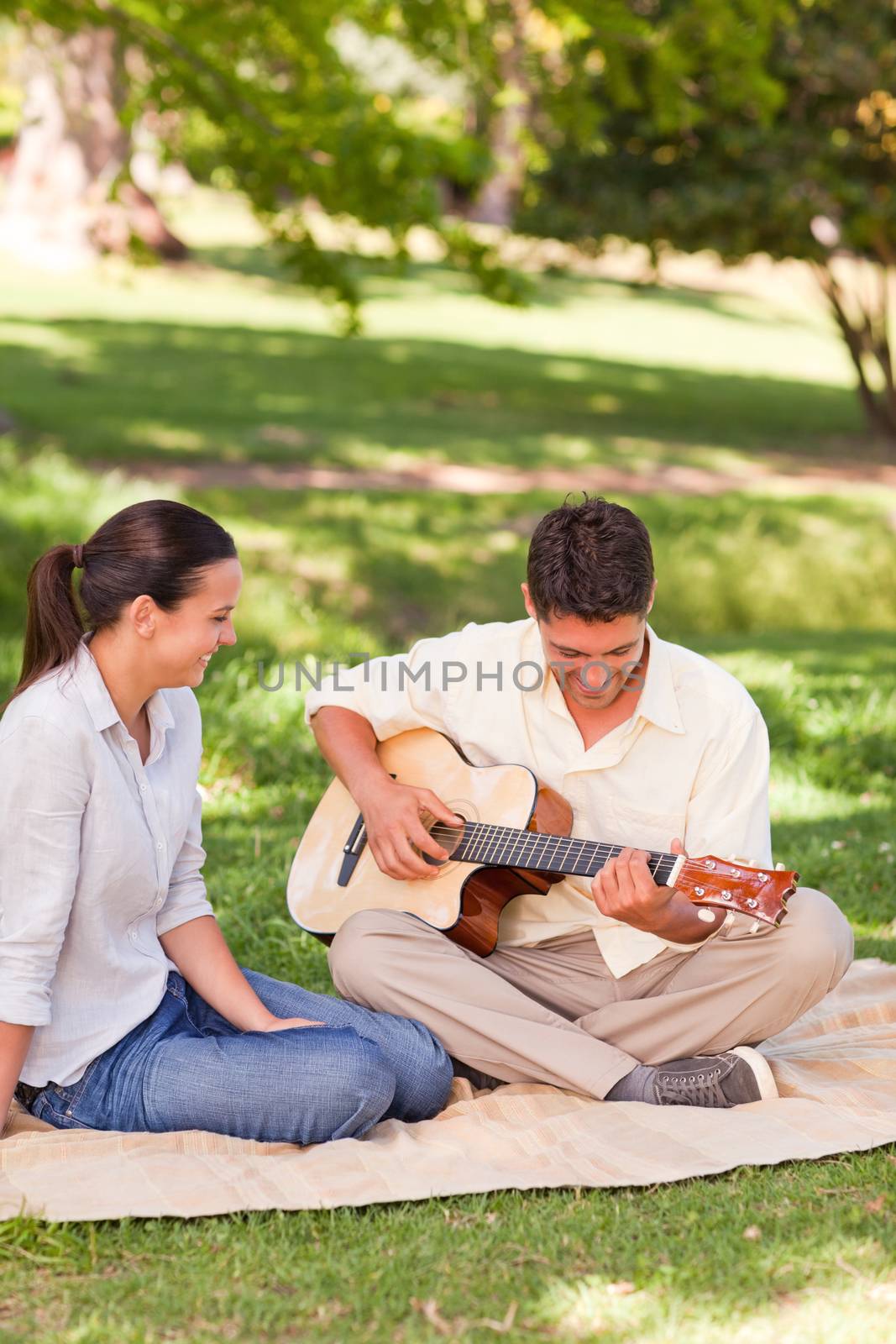 Romantic man playing guitar for his wife in a park