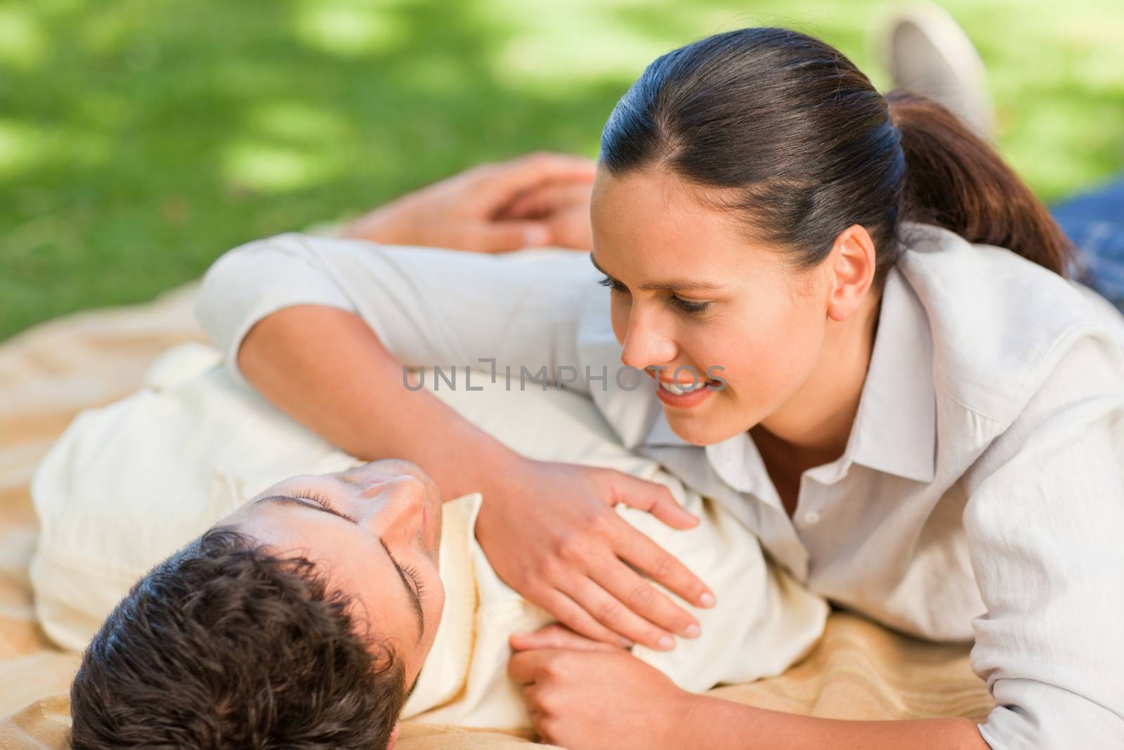 Happy couple lying down in the park during the summer