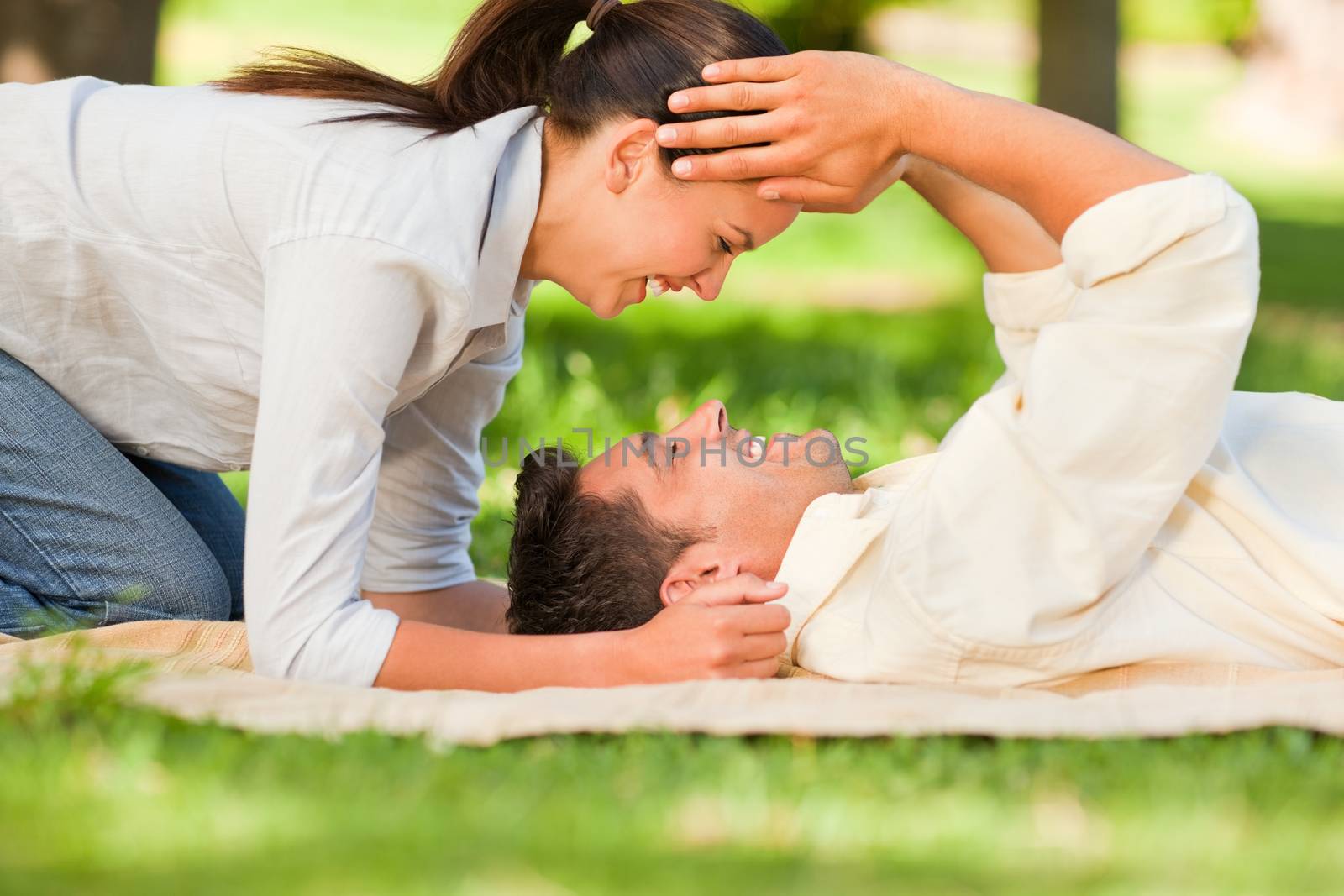 Happy couple lying down in the park during the summer