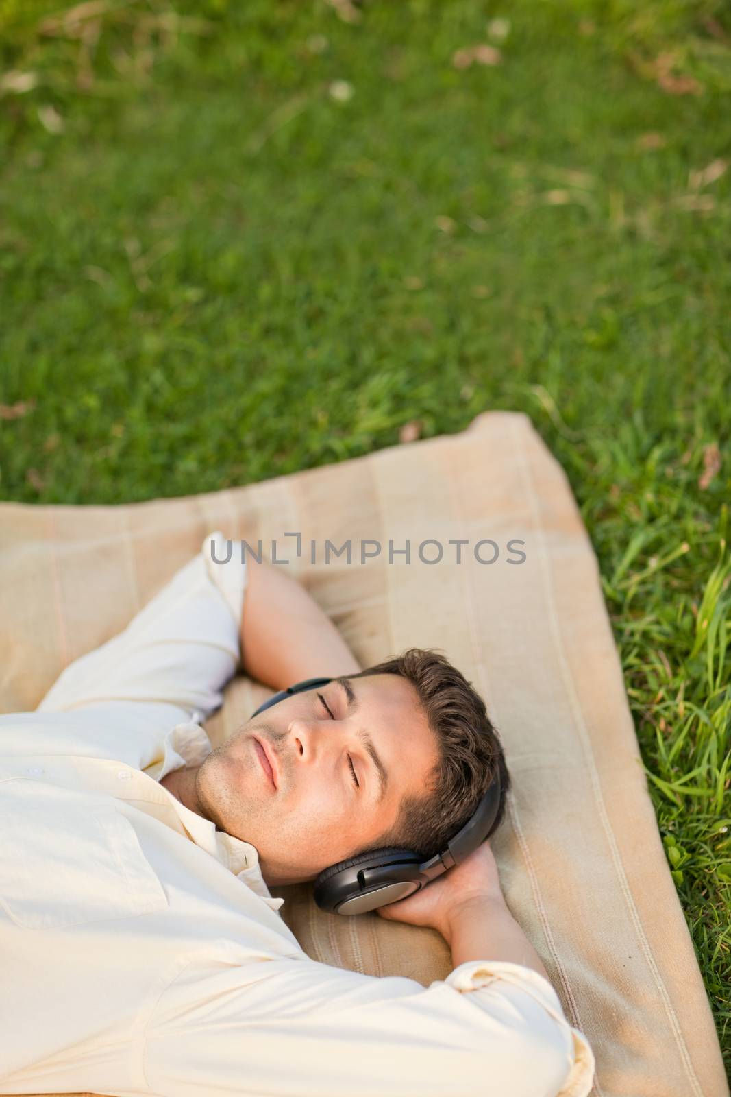 Young man listening to music in the park durrig the summer