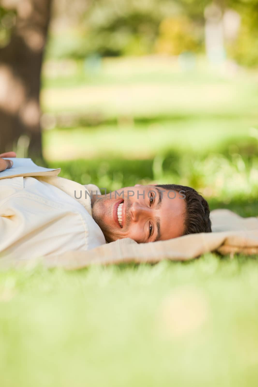 Man lying in the park with his book by Wavebreakmedia