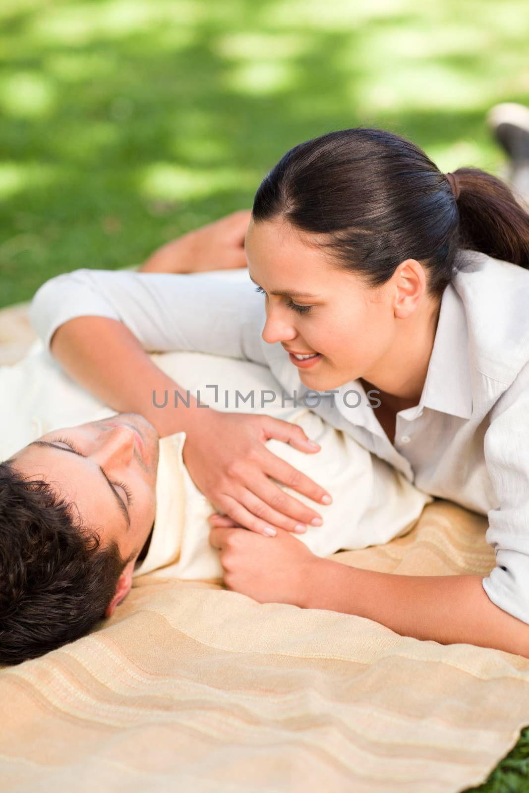 Happy couple lying down in the park during the summer