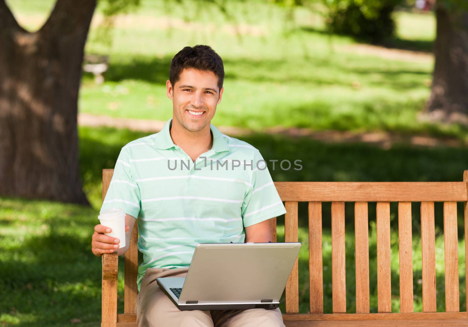 Man working on his laptop in the park during the summer 