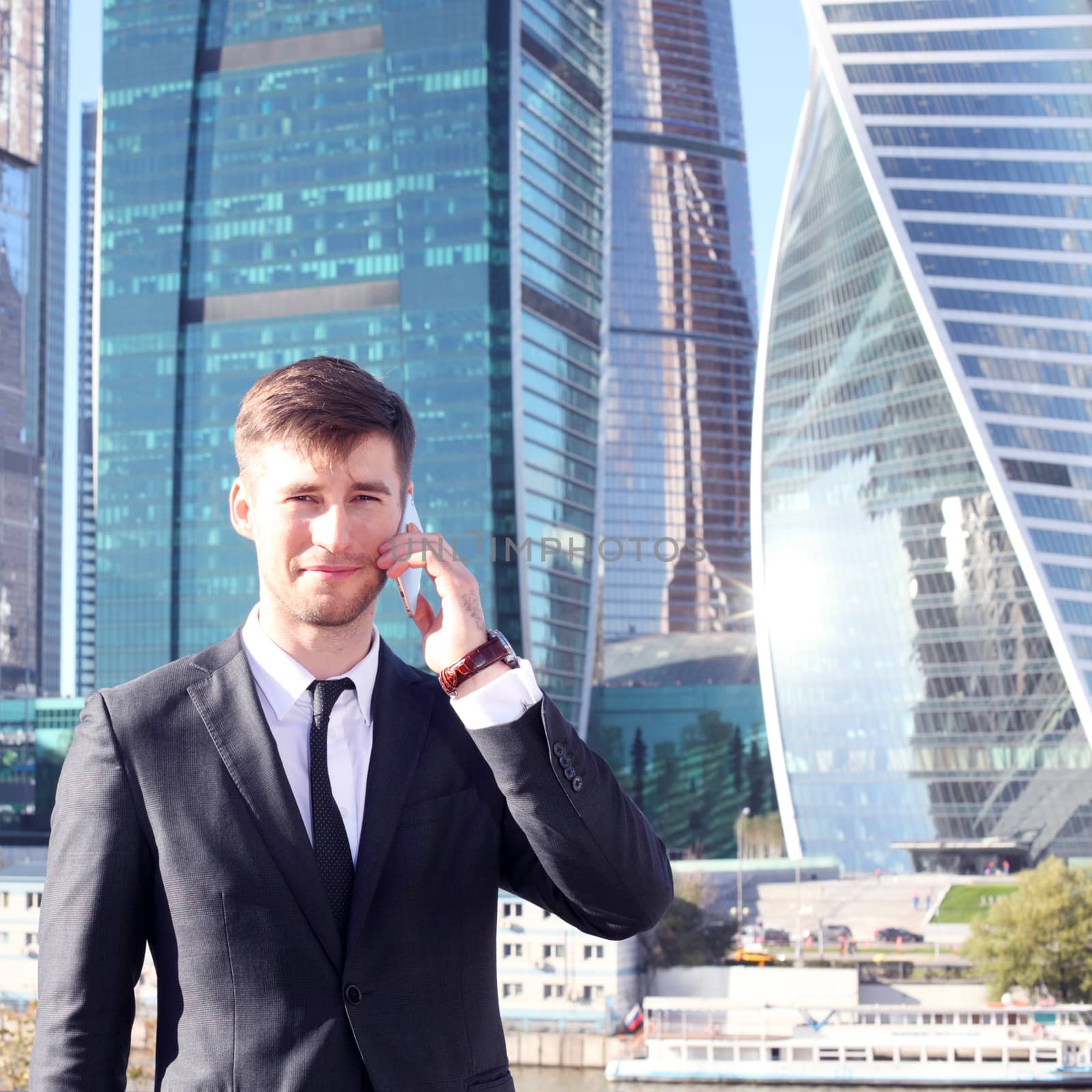 Businessman talking on the phone on skyscraper background