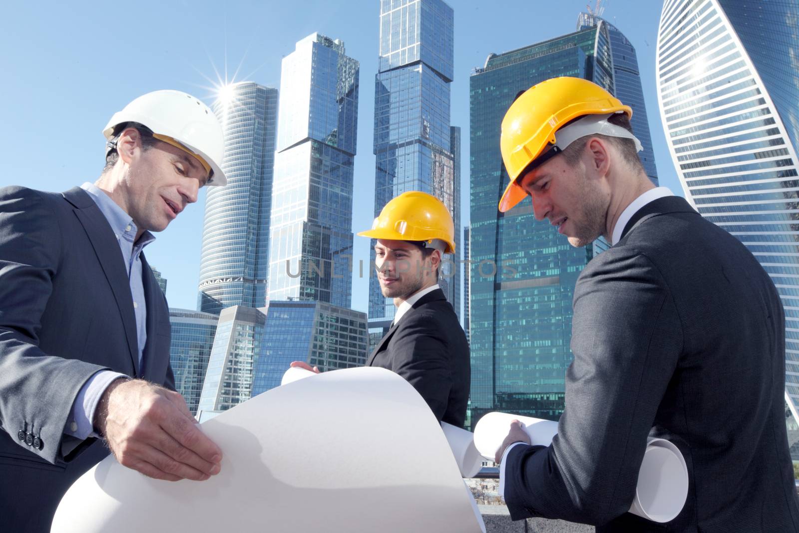 Architects with blueprint at skyscrapers background