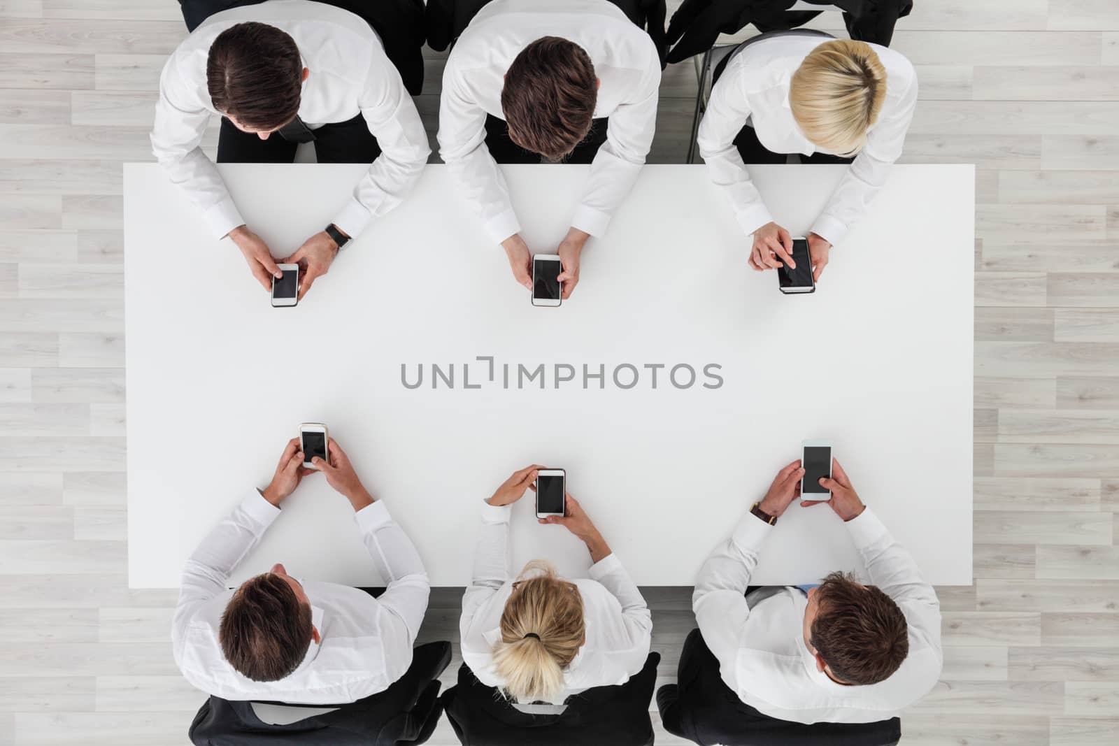 Business people using smartphones sitting at table in office, white copy space background