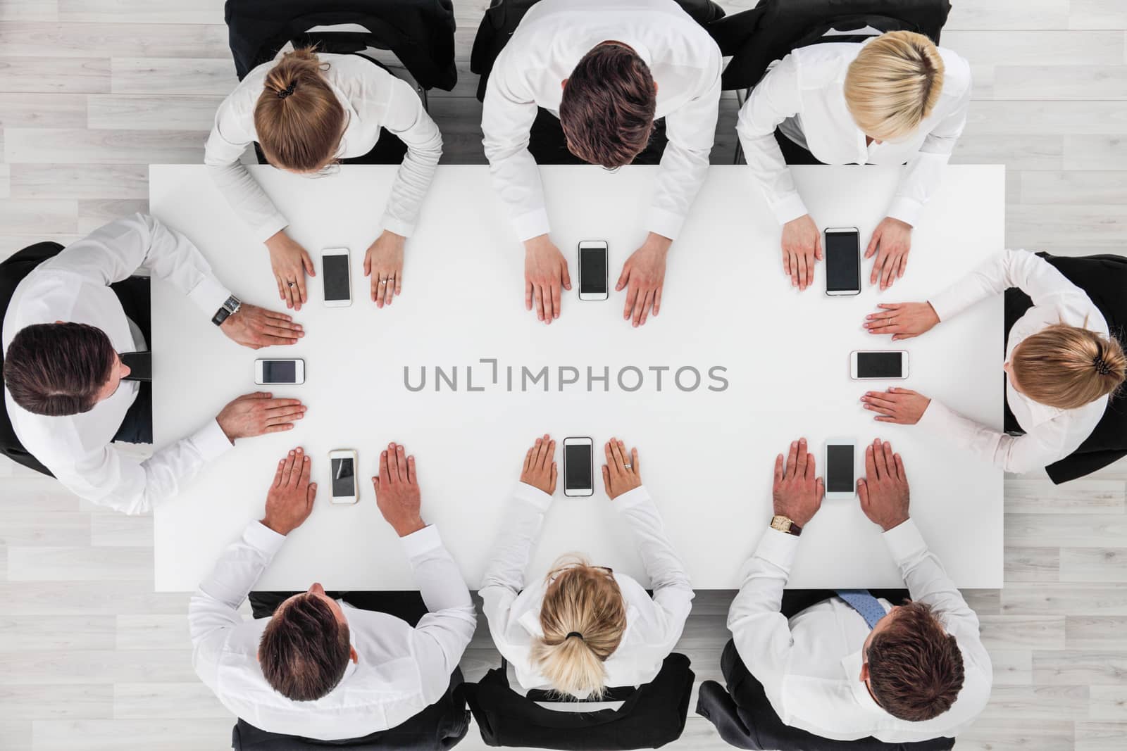 Business people not using smartphones sitting around white table