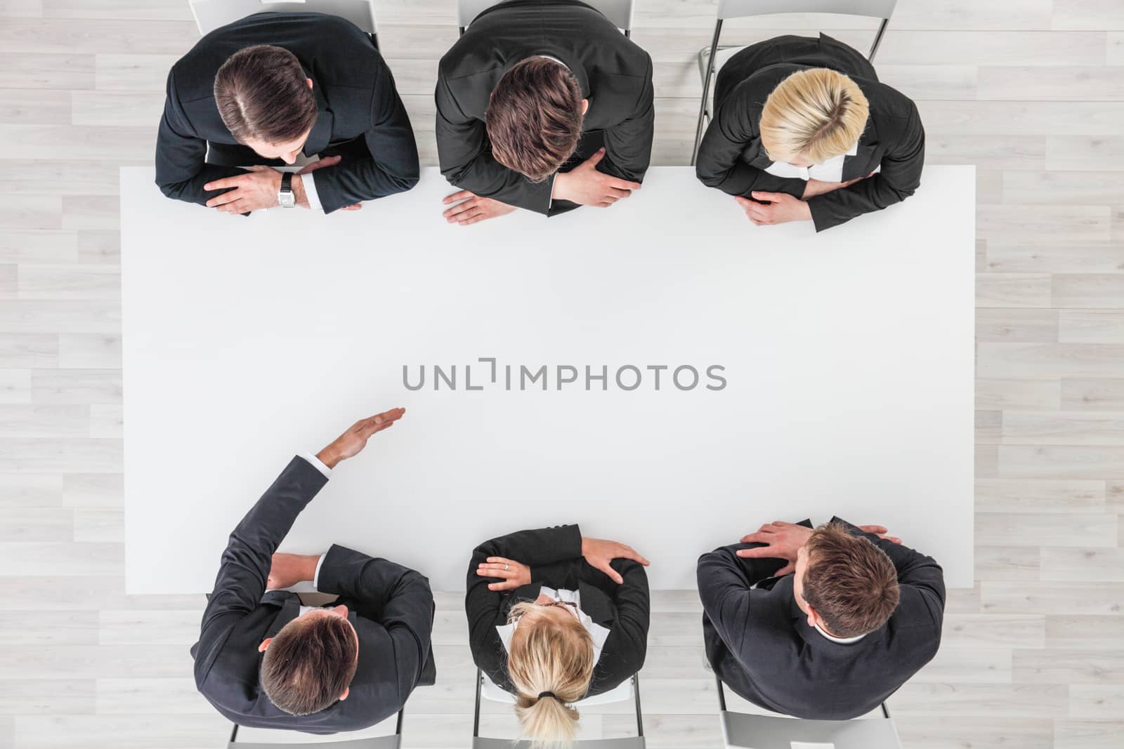 Business people sitting around empty table, business man pointing to blank copy space in the middle