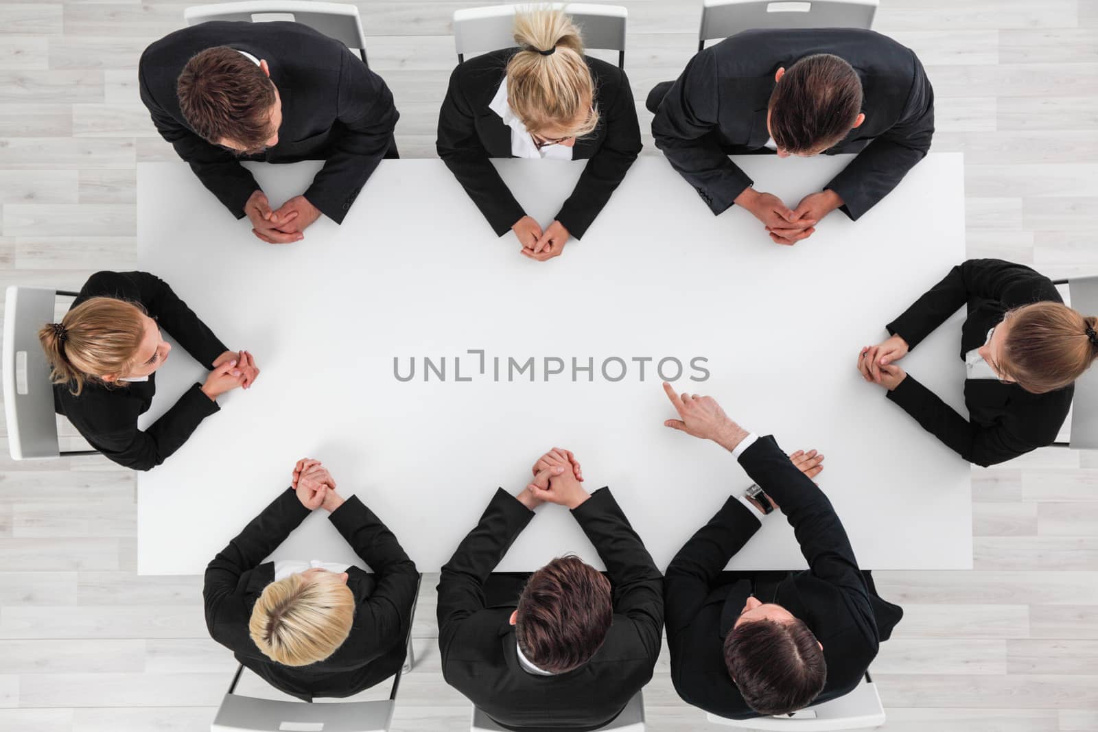 Business people sitting around empty table, business man pointing to blank copy space in the middle