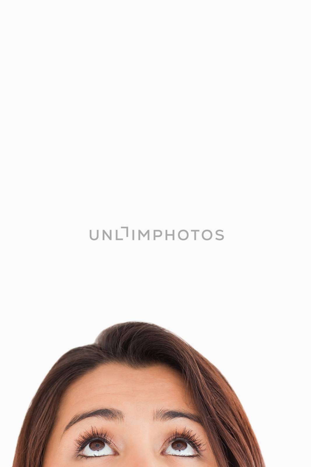 Woman eyes looking up while standing against a white background