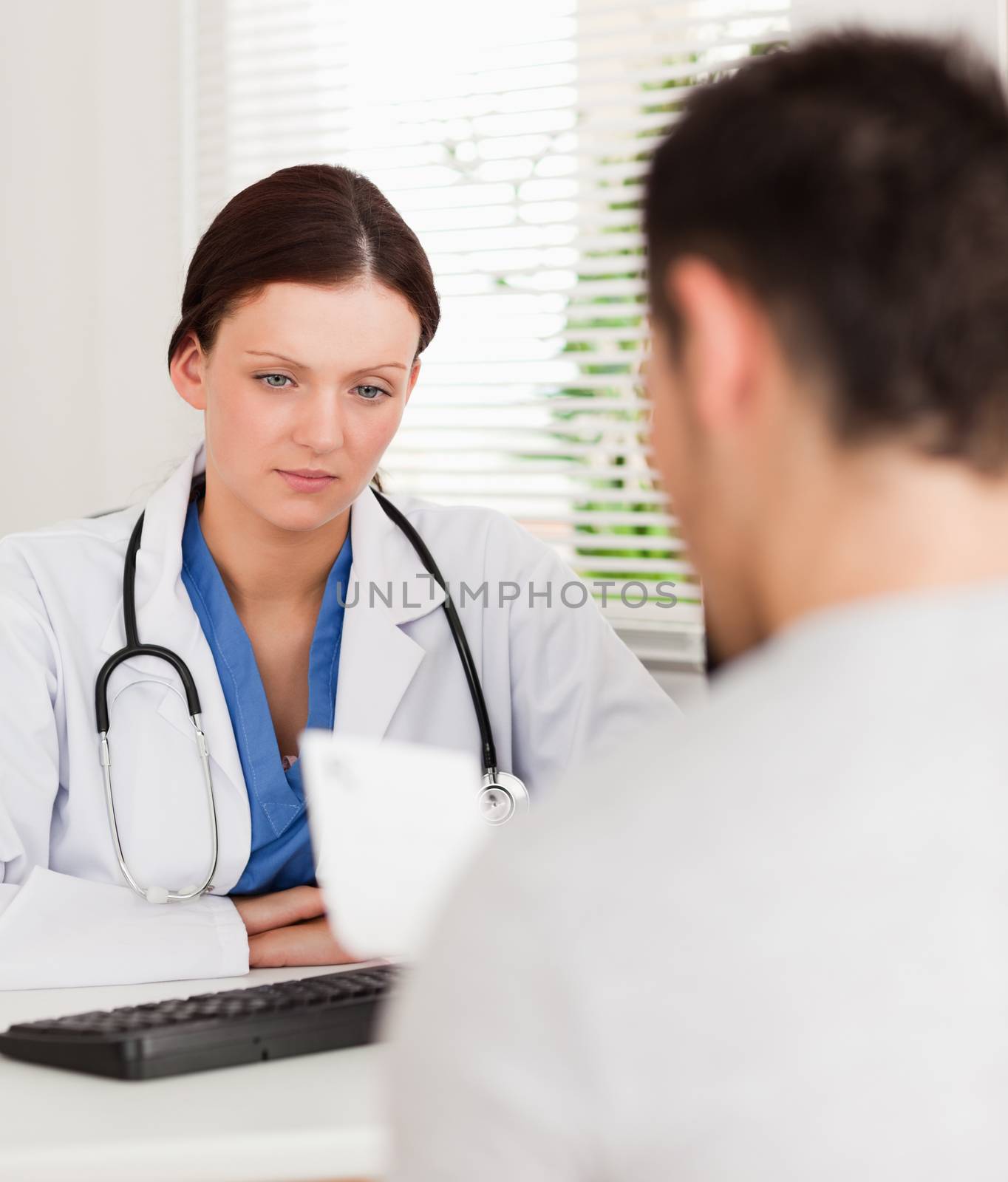 A female doctor and her patient are sitting in an office whilst patient reads prescription