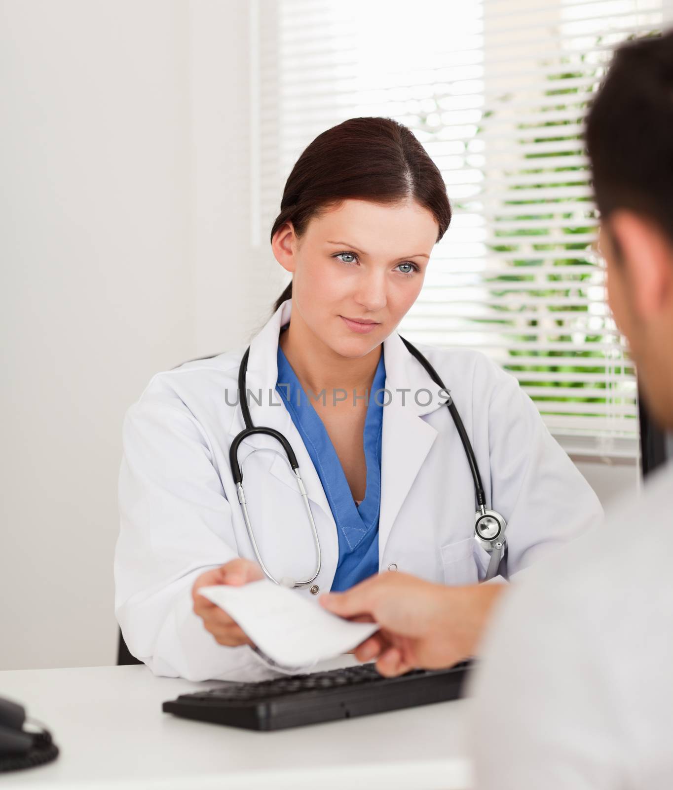 A female doctor is presenting a prescription to a patient in office