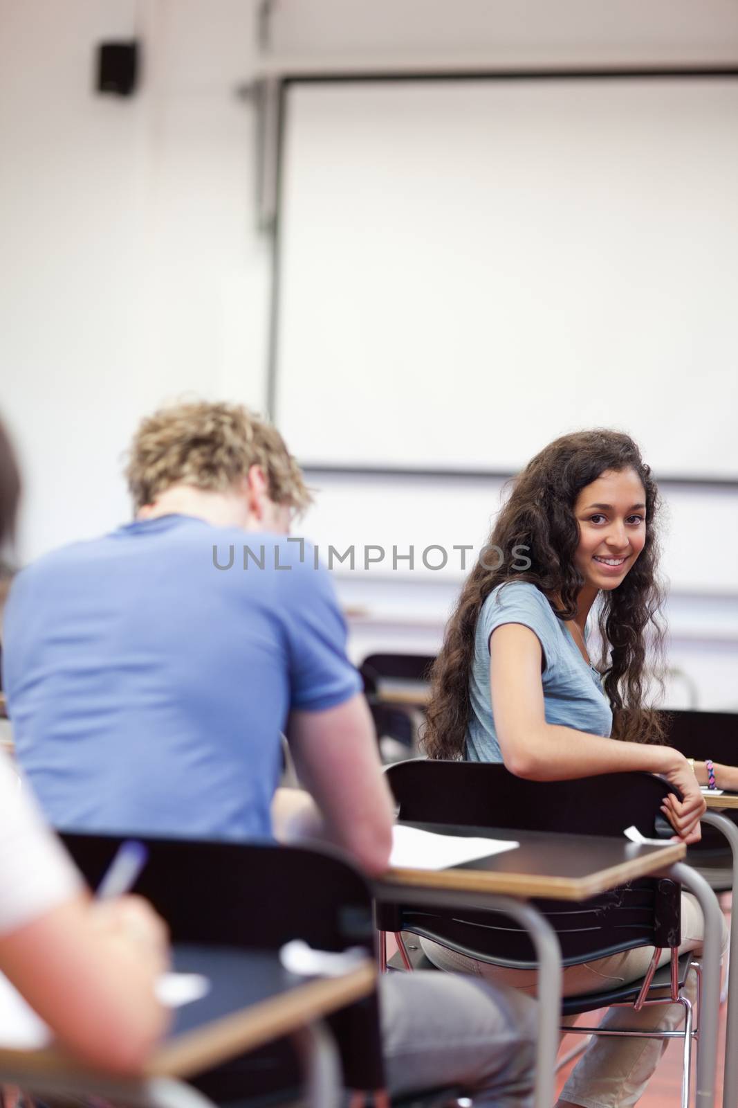 Portrait of a playful student sitting at a table in a classroom