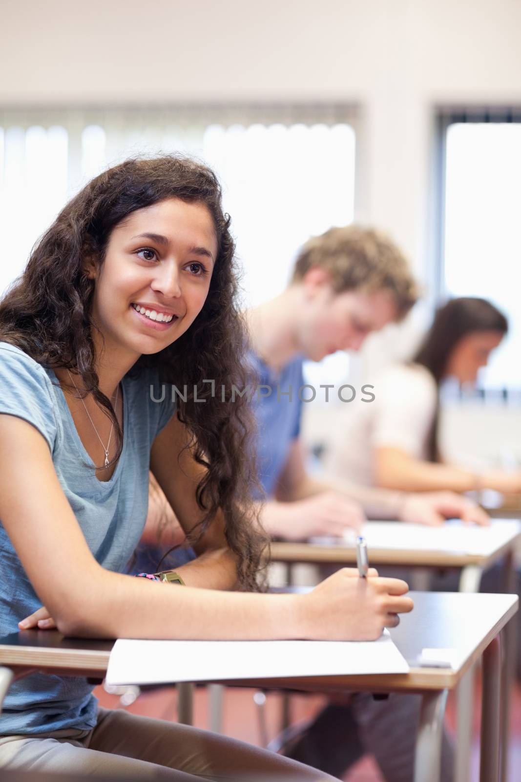 Portrait of happy young adults writing in a classroom