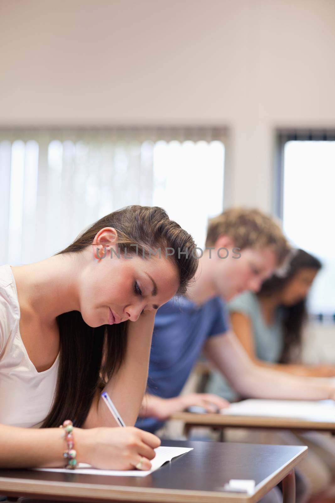 Portrait of a studious woman writing in a classroom