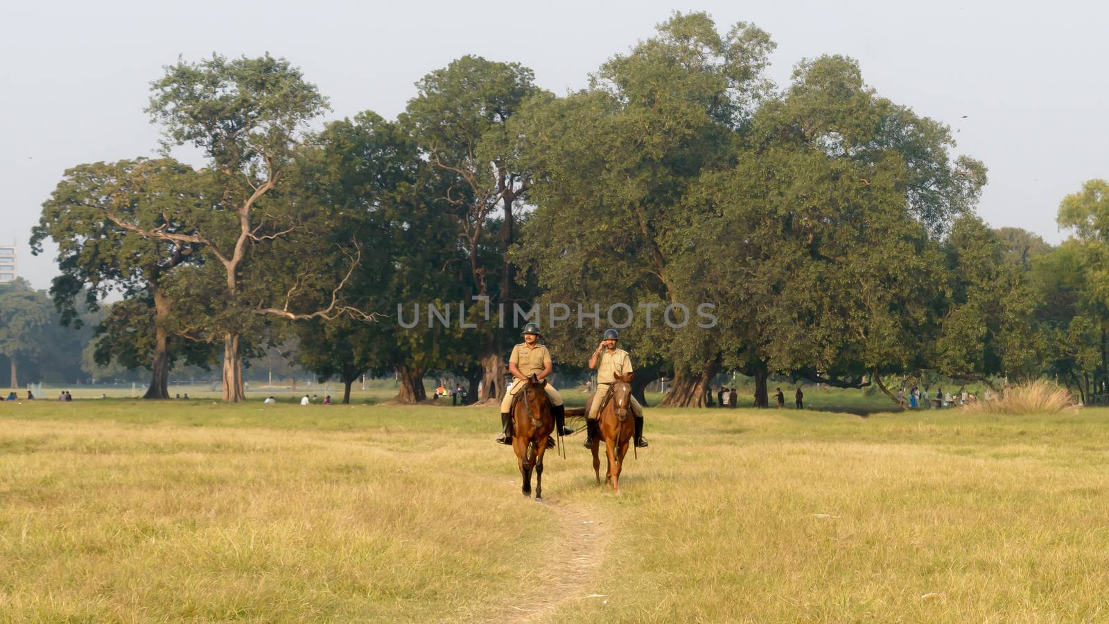 Kolkata Mounted Police personnel keep galloping in style, vigilance and patrolling Maidan area of Brigade Parade ground in Summer sunset time. Eden Gardens, Kolkata City, West Bengal, India, May 2019