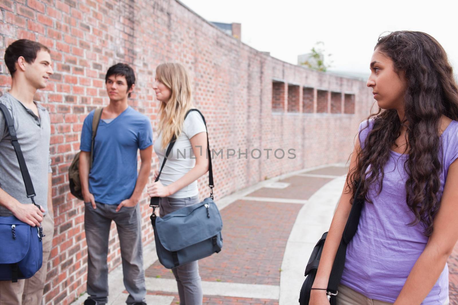 Lonely student looking at her classmates talking in a yard