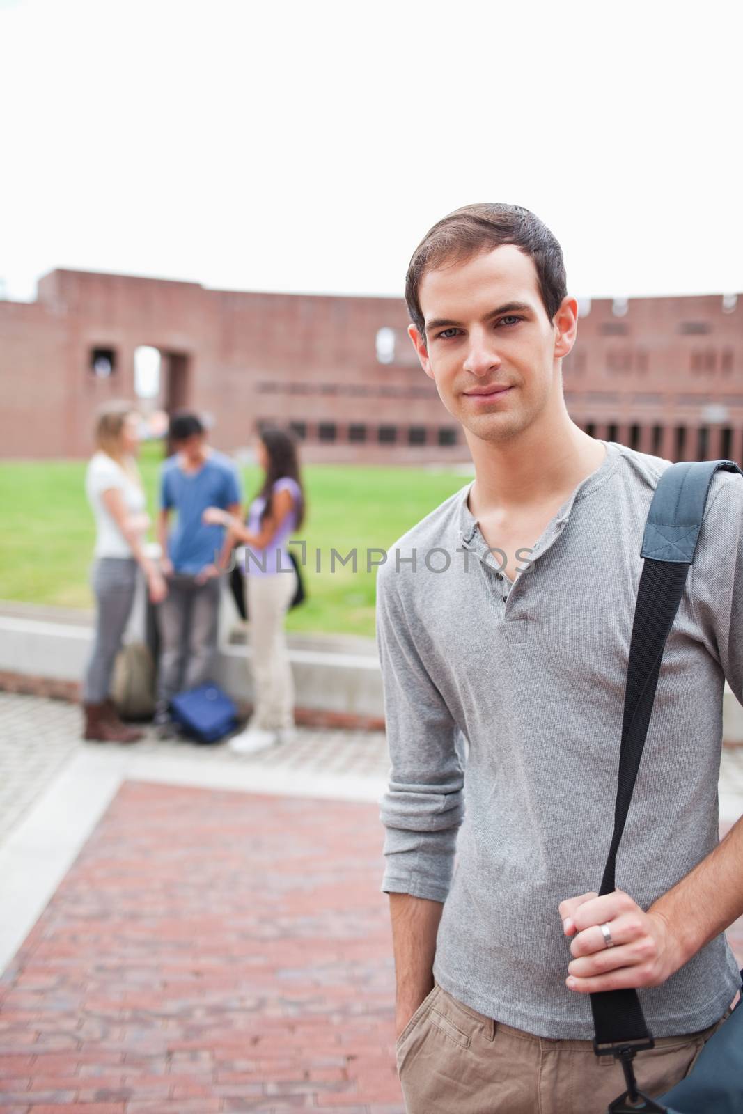 Portrait of a student posing while his classmates are talking by Wavebreakmedia