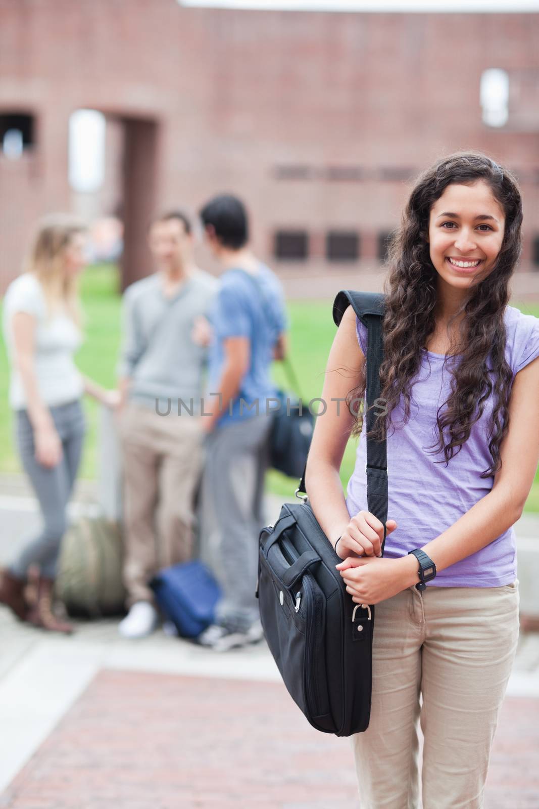 Portrait of a smiling student posing while his classmates are talking by Wavebreakmedia