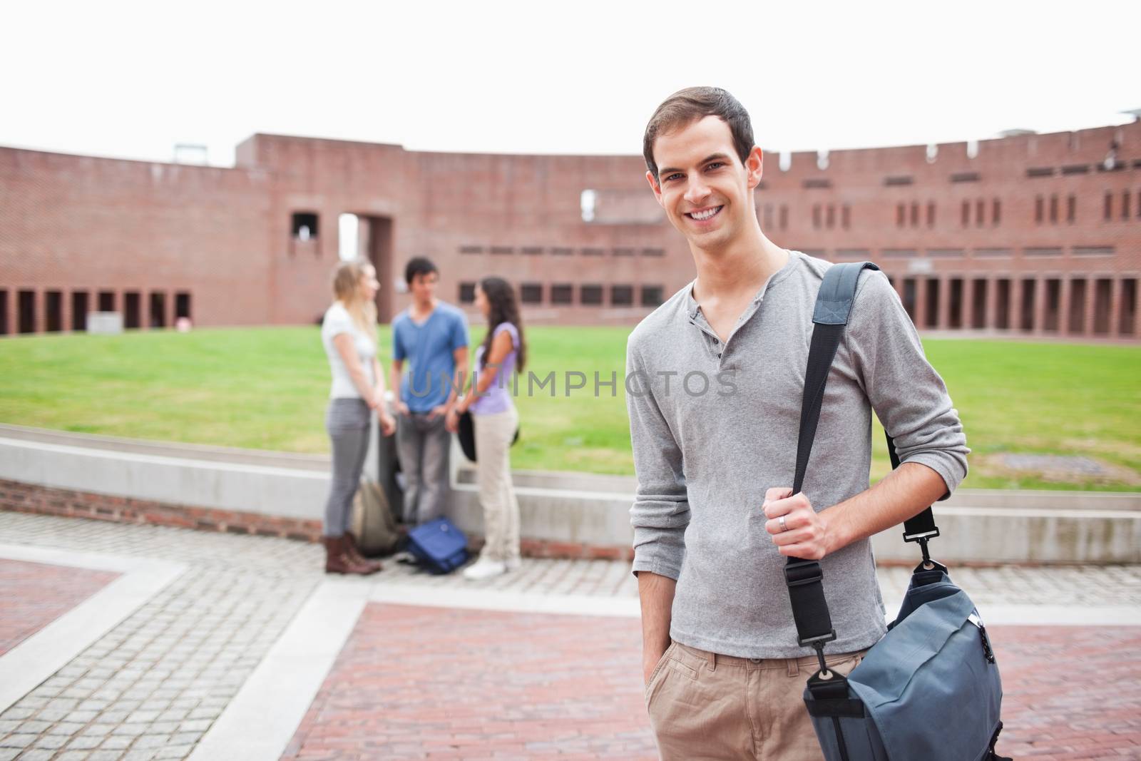 Student posing while his classmates are talking in a yard