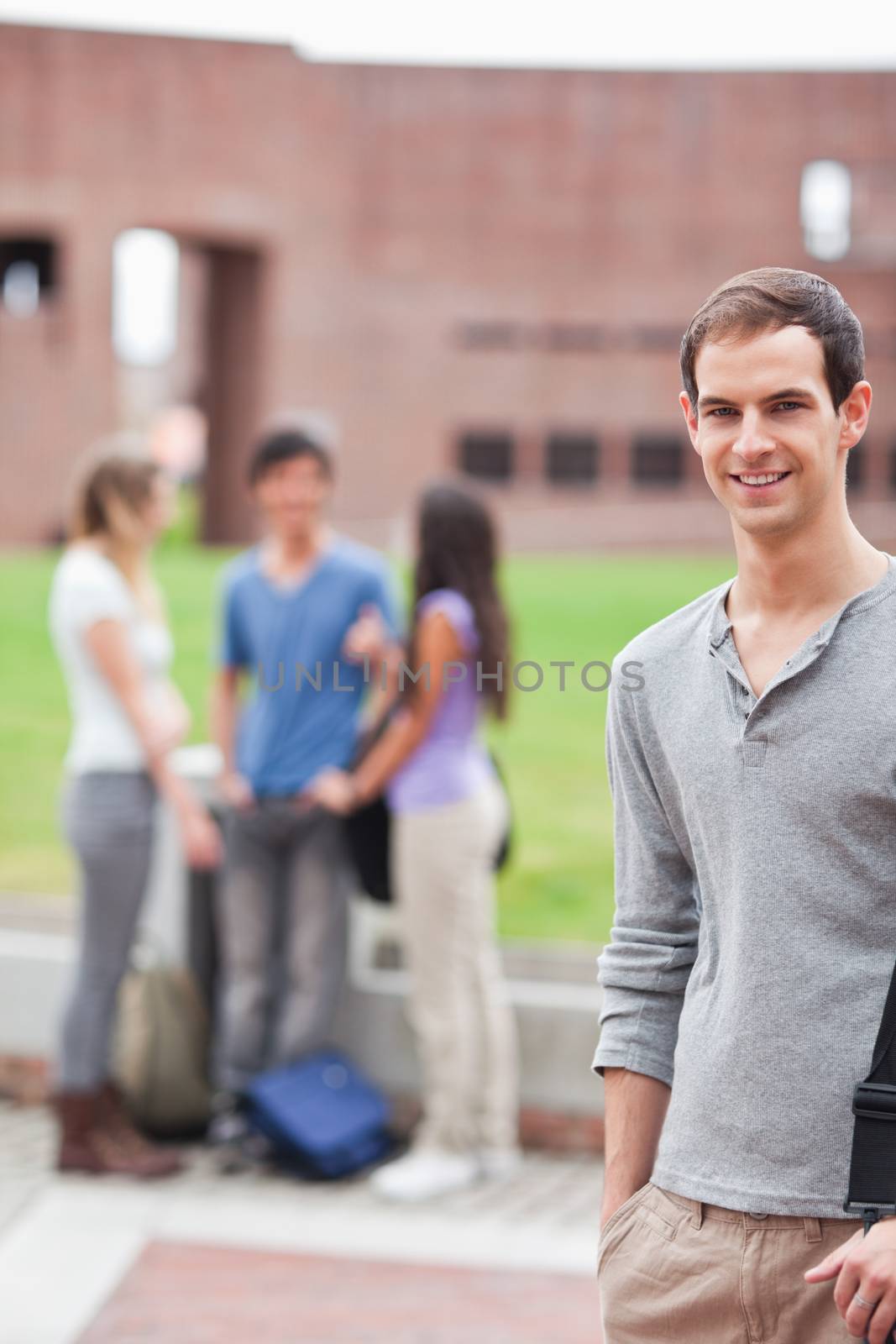 Portrait of a male student posing while his classmates are talking by Wavebreakmedia