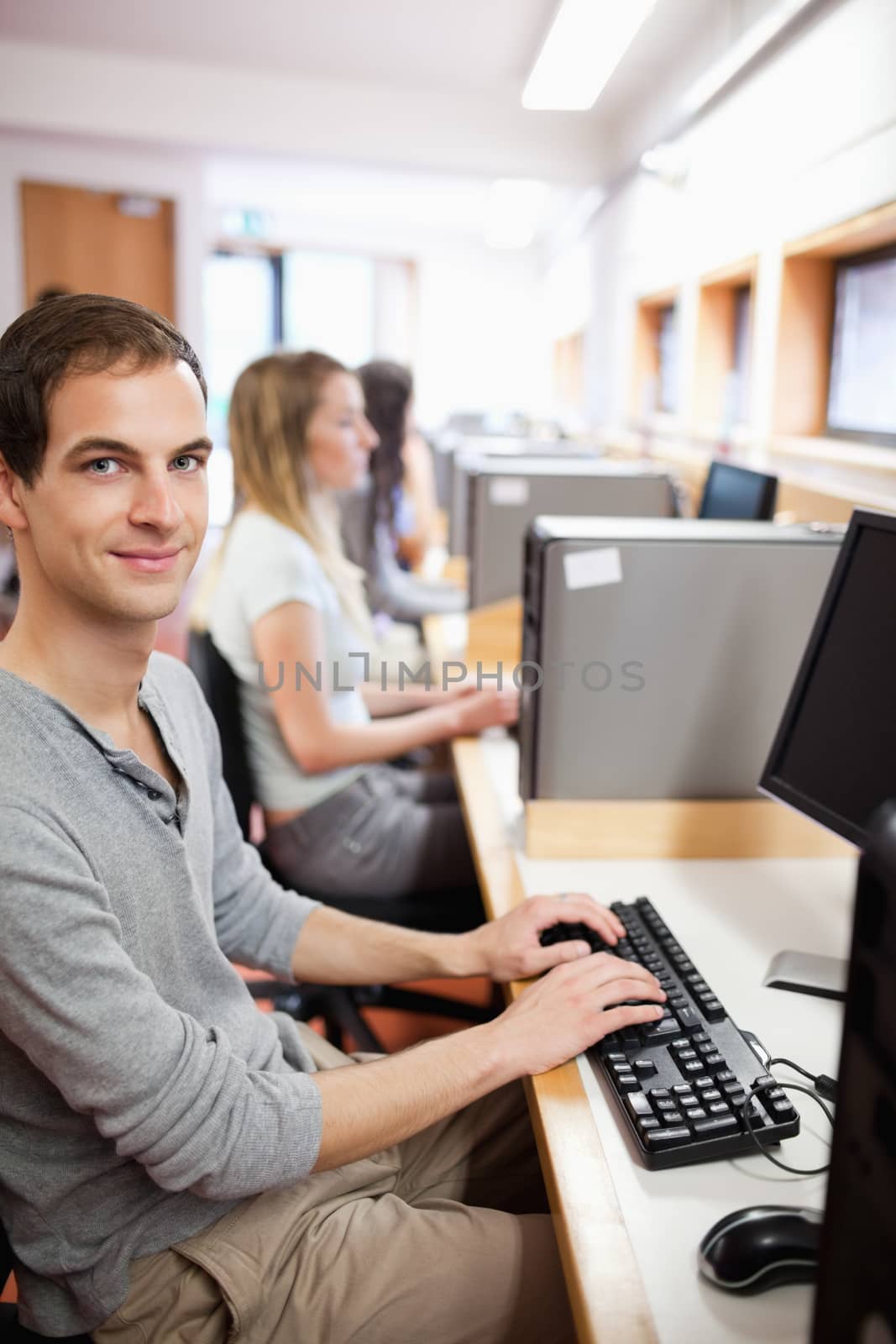 Portrait of a young male student posing with a computer in an IT room