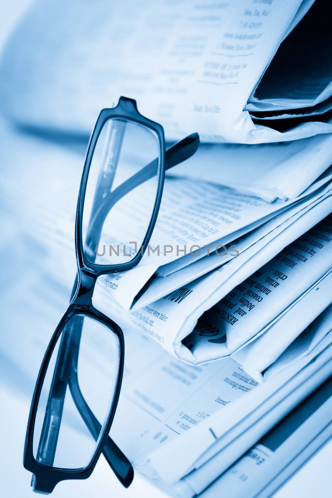Newspapers and black glasses against a white a background