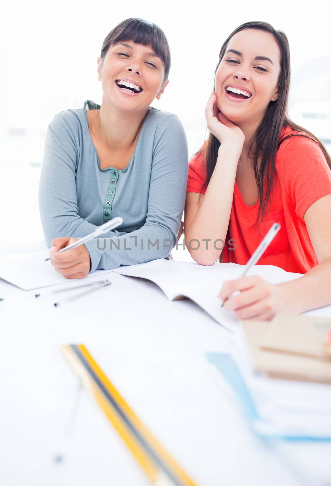 A pair of girls laughing as they look at the camera by Wavebreakmedia