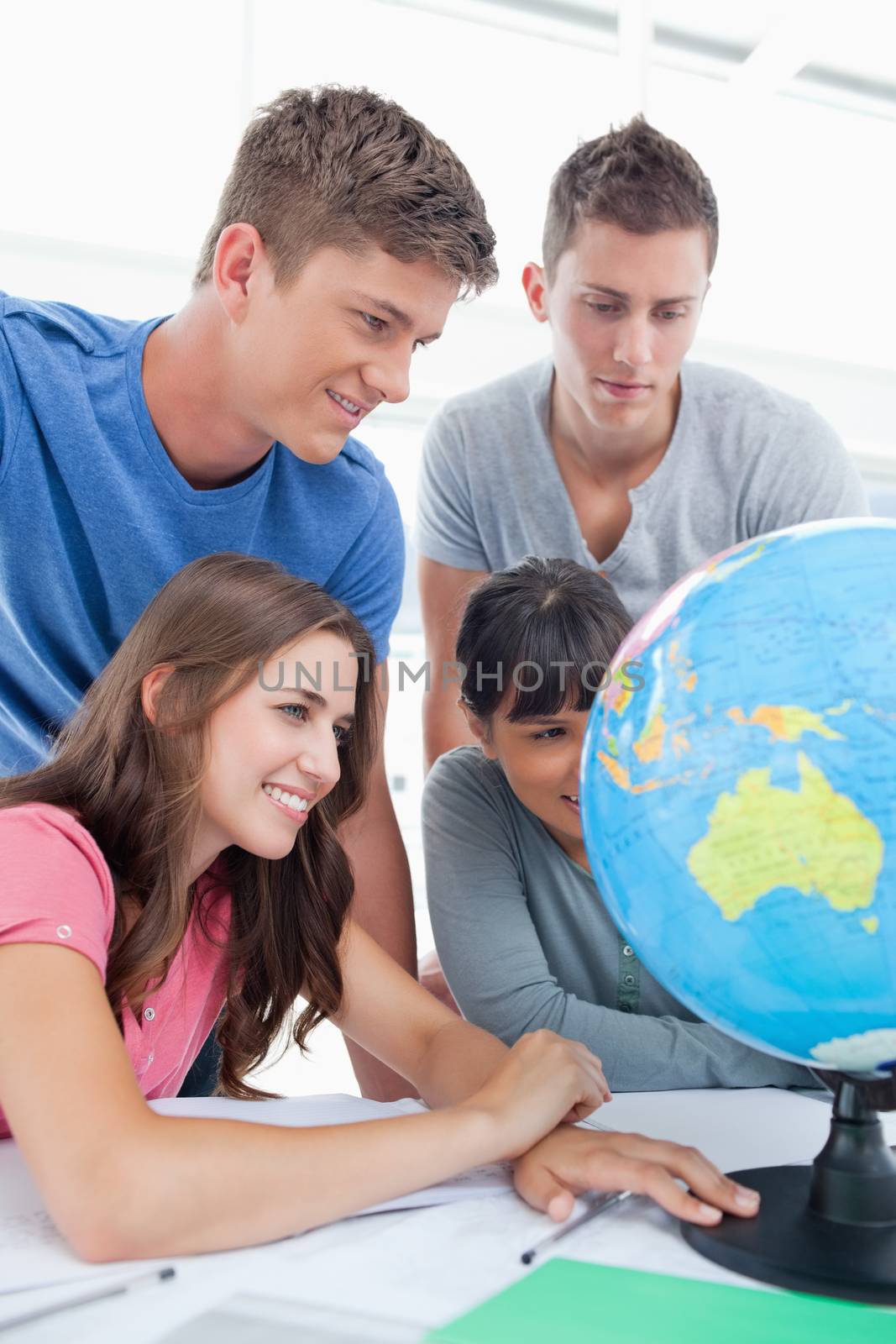 A close up shot of people looking at the globe in front of them