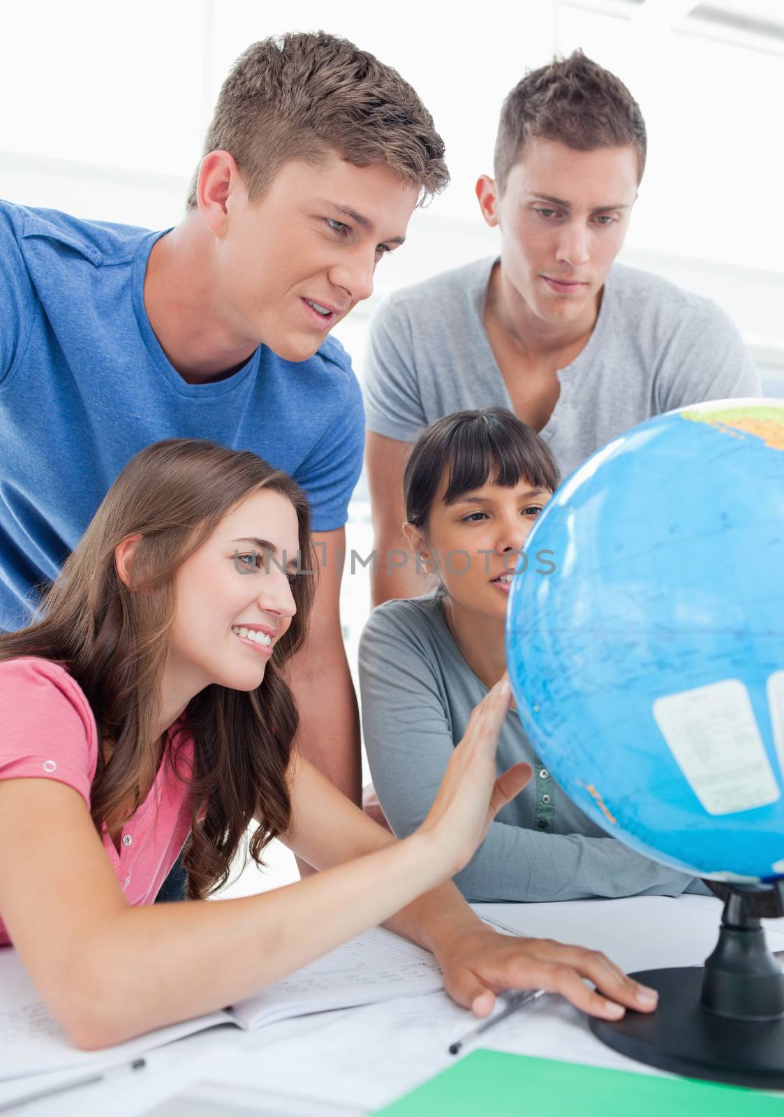 A close up shot of four people sitting in front of the globe and looking for a place 