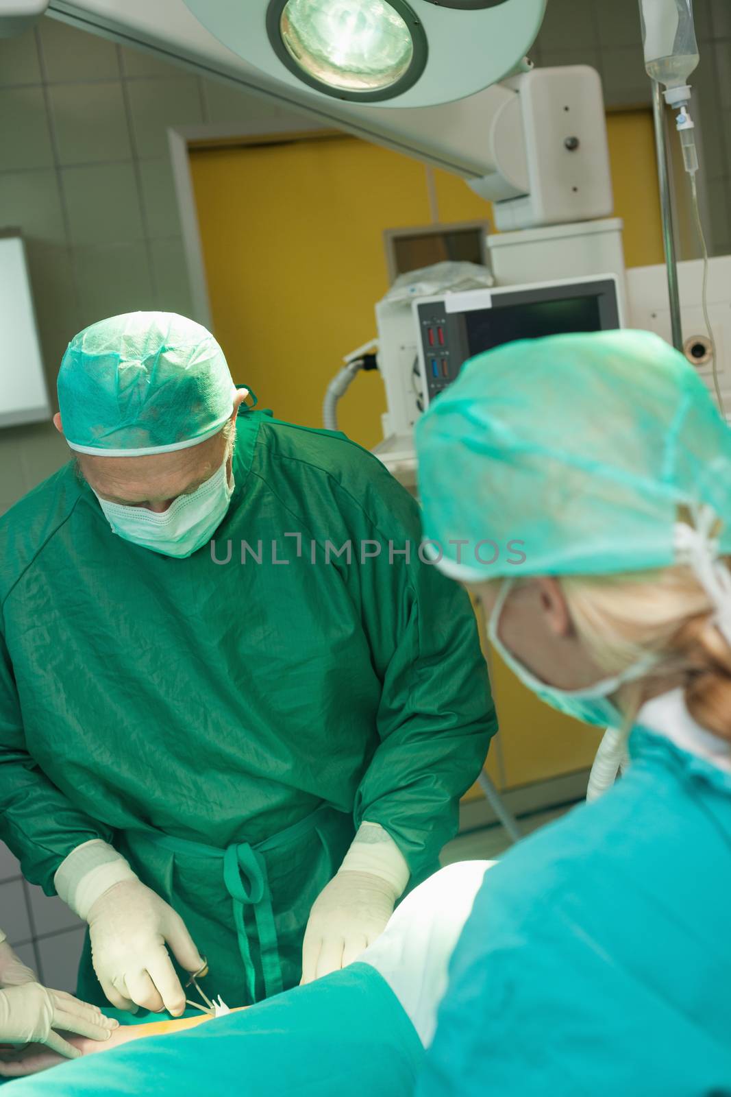 Surgeon holding scissors while operating by Wavebreakmedia