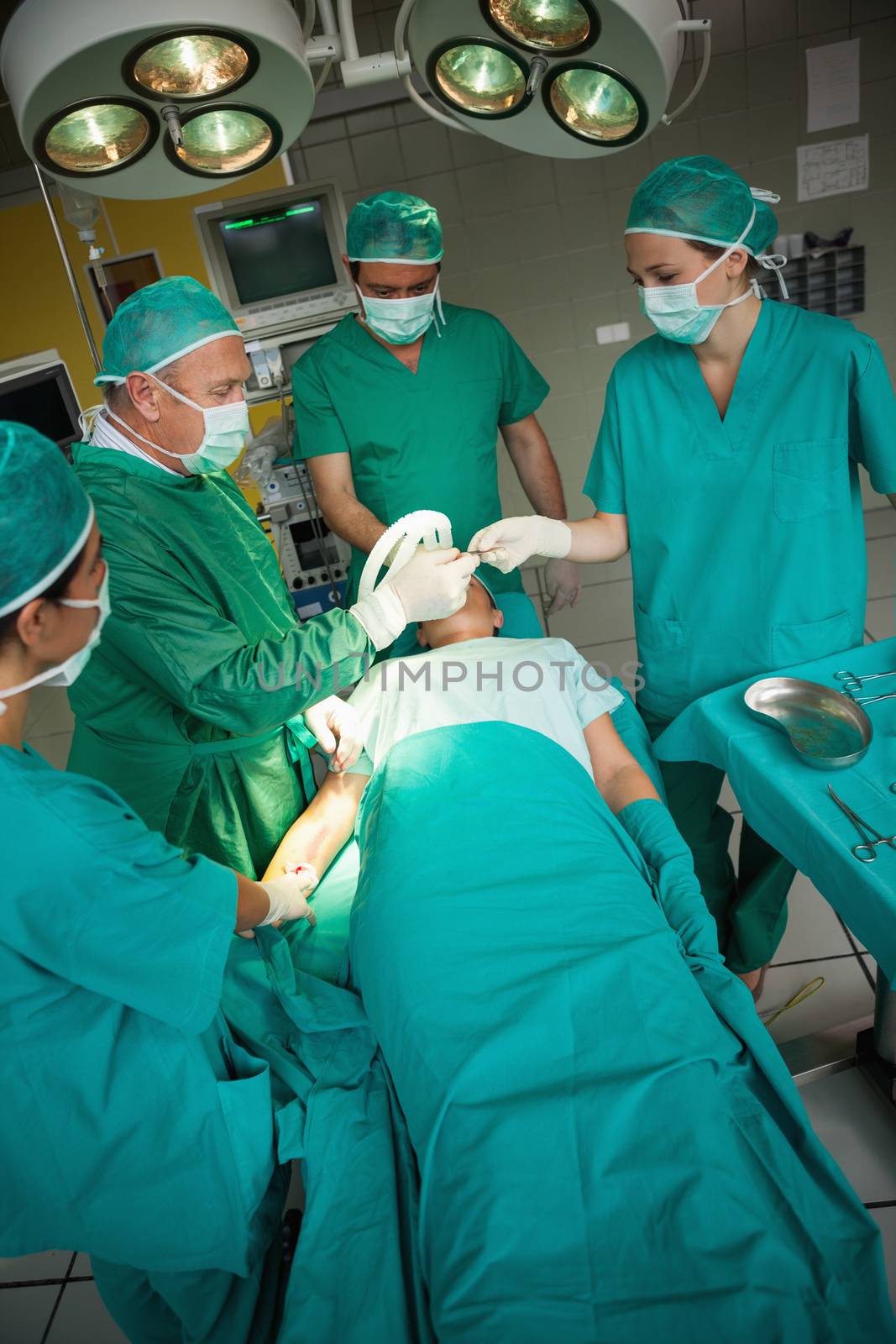 Surgeon working on the arm of a patient with a team of surgeons in a surgical room