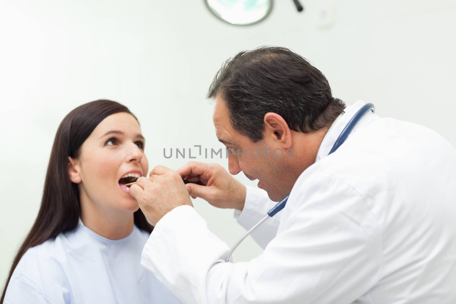 Doctor looking at the mouth of his patient in an examination room