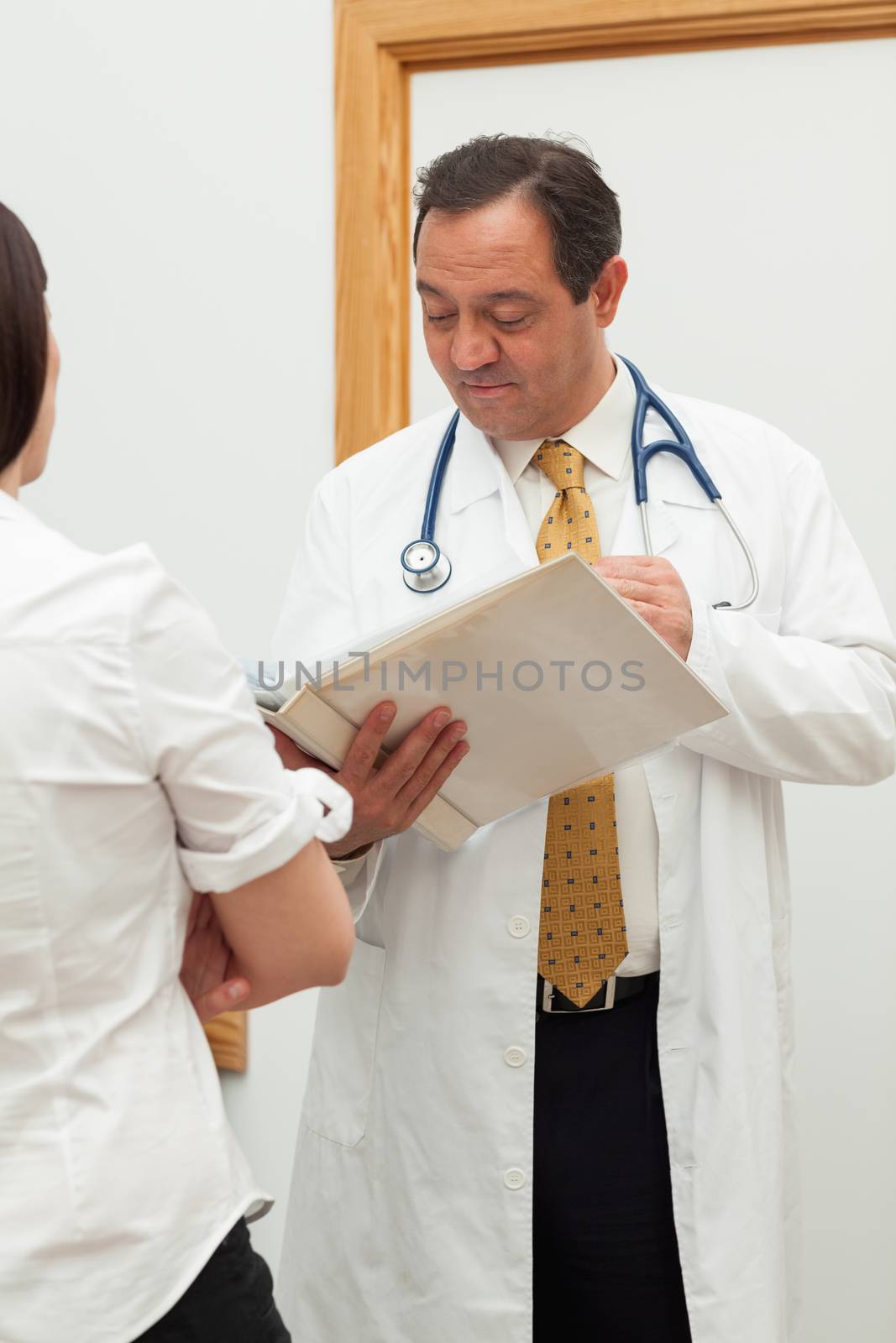 Doctor looking into a file while talking to a woman in a hallway