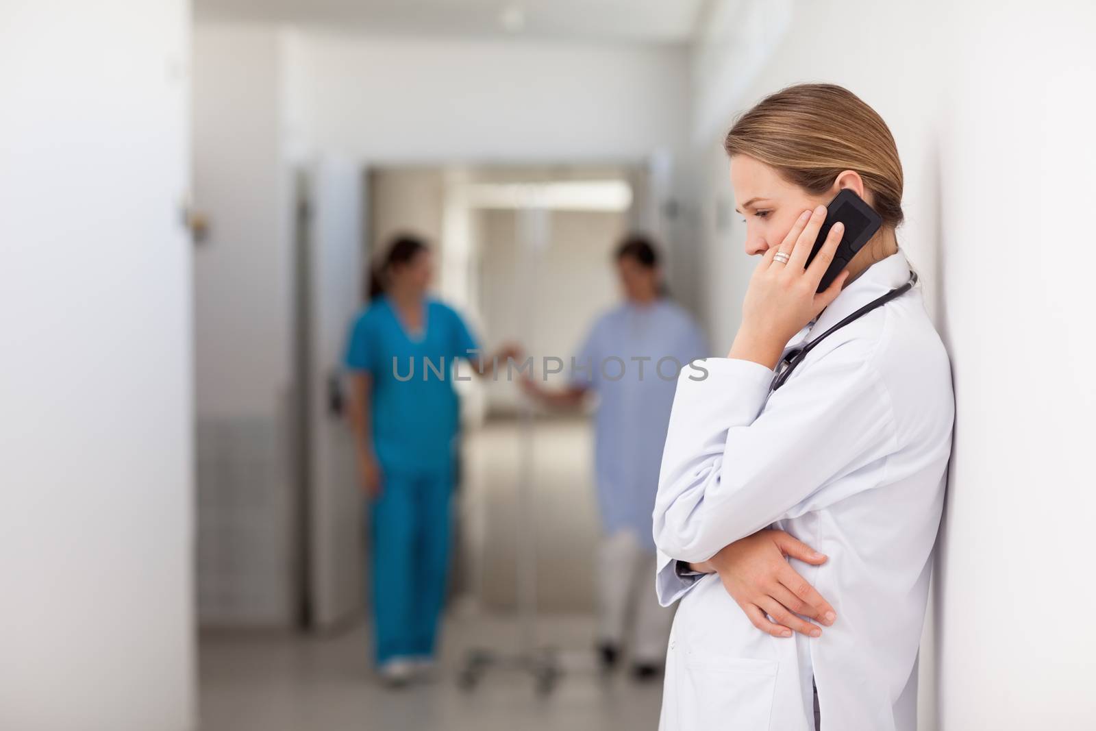 Woman doctor phoning on the hallway by Wavebreakmedia