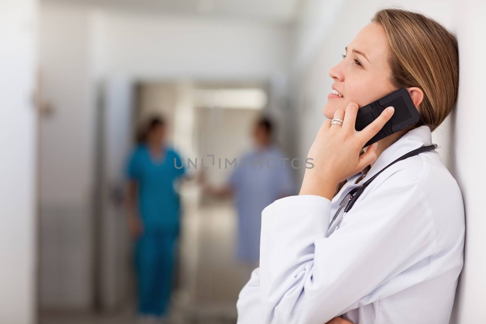 Doctor against a wall phoning in a hallway