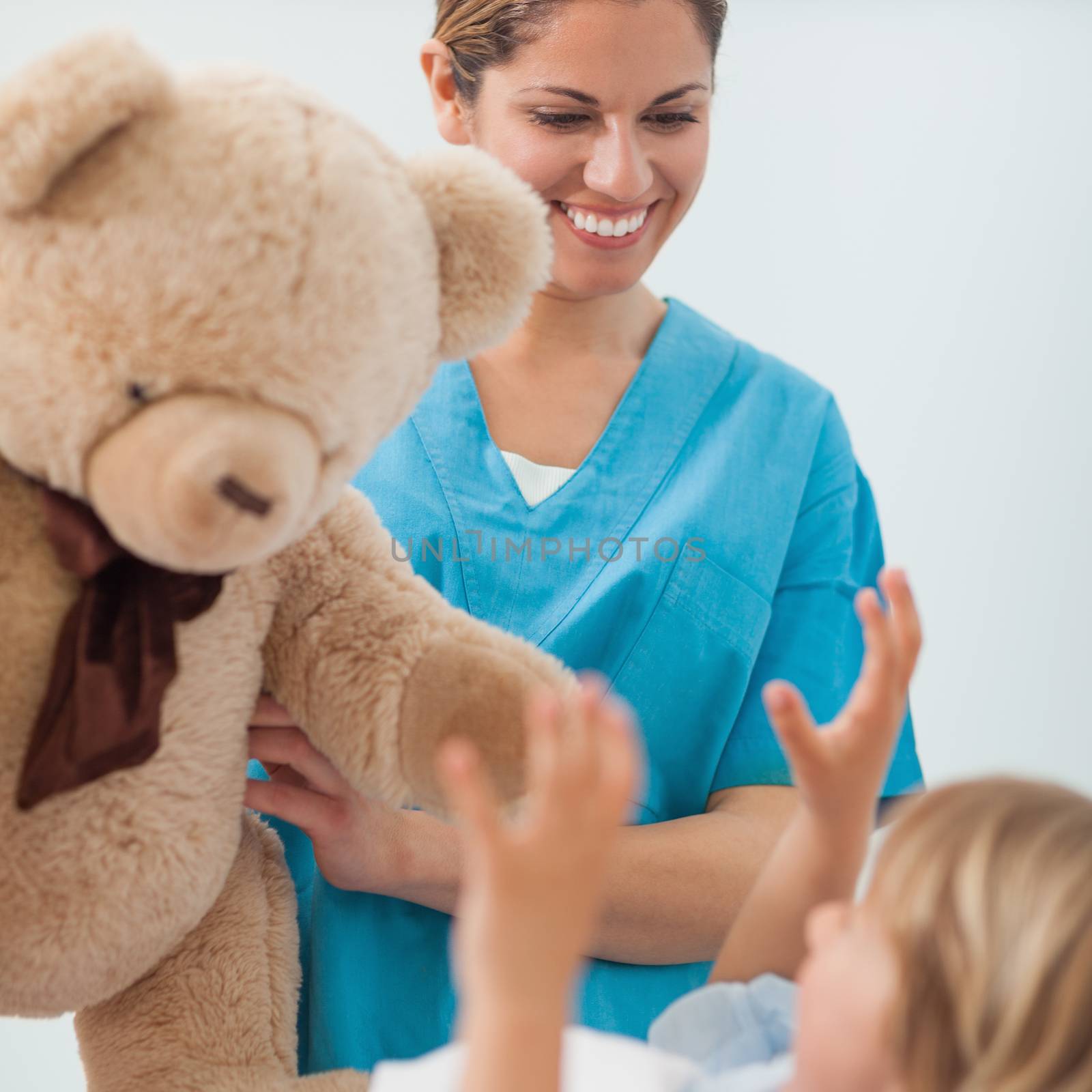Smiling nurse holding a teddy bear in hospital ward