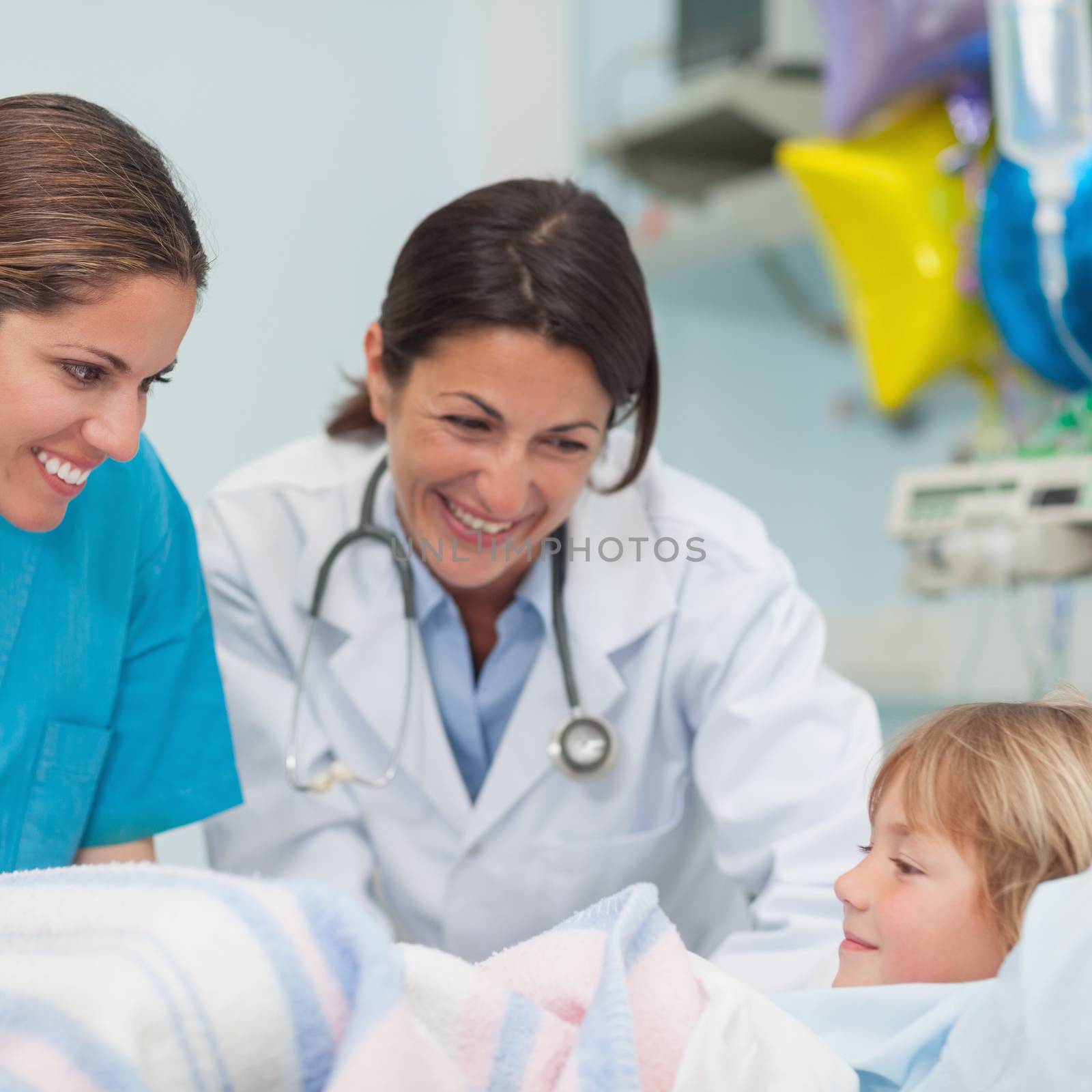 Doctor and nurse smiling to a child in hospital ward