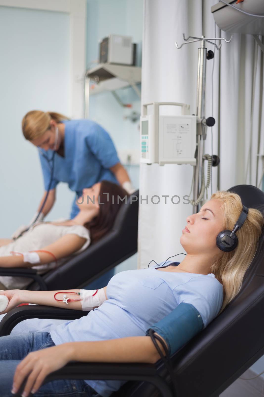 Female patient listening music while being transfused in hospital ward