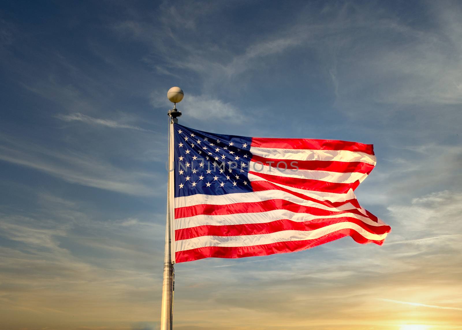 An American flag blowing in the wind over a blue sky