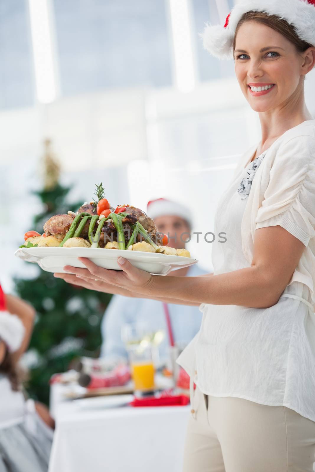 Attractive woman bringing roast chicken at a christmas dinner and looking at camera