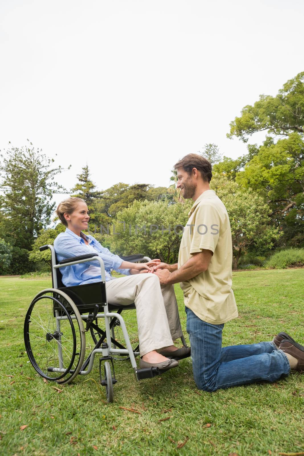 Blonde woman in wheelchair with partner kneeling beside her by Wavebreakmedia
