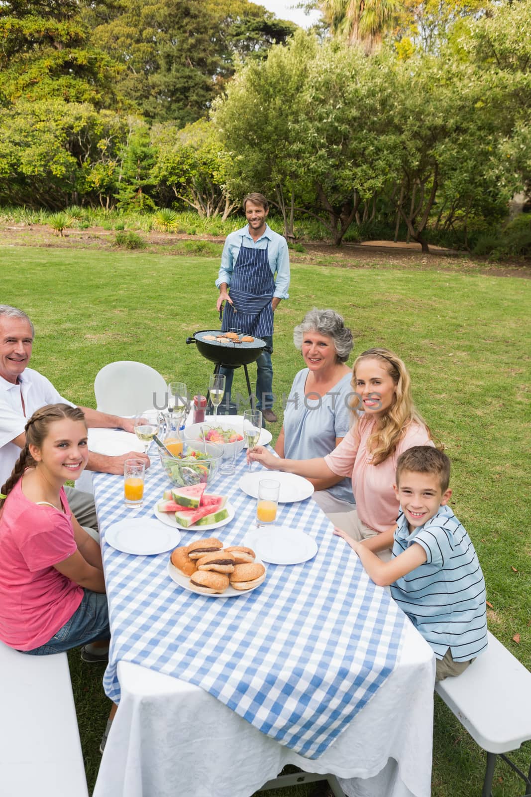 Cheerful extended family having a barbecue outside smiling at camer