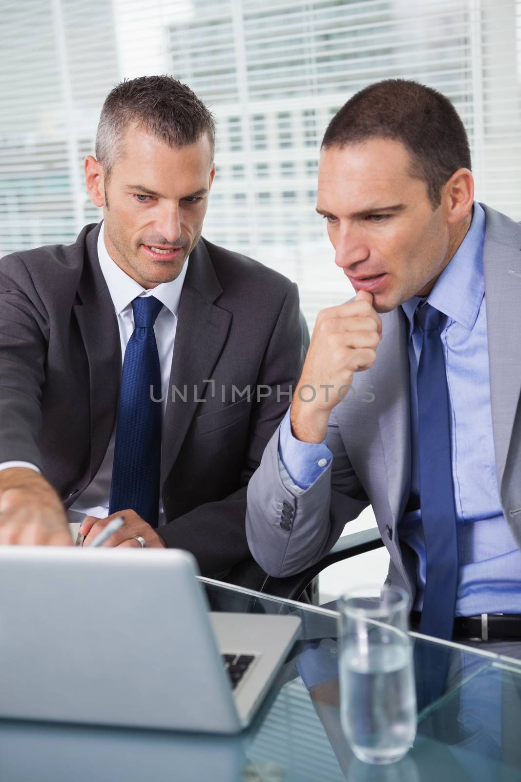 Concentrated businessmen analyzing documents on their laptop by Wavebreakmedia